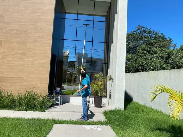Profissional limpando a fachada de vidro de uma casa no Alphaville